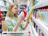 Une femme compare des produits ménagers dans une grande surface